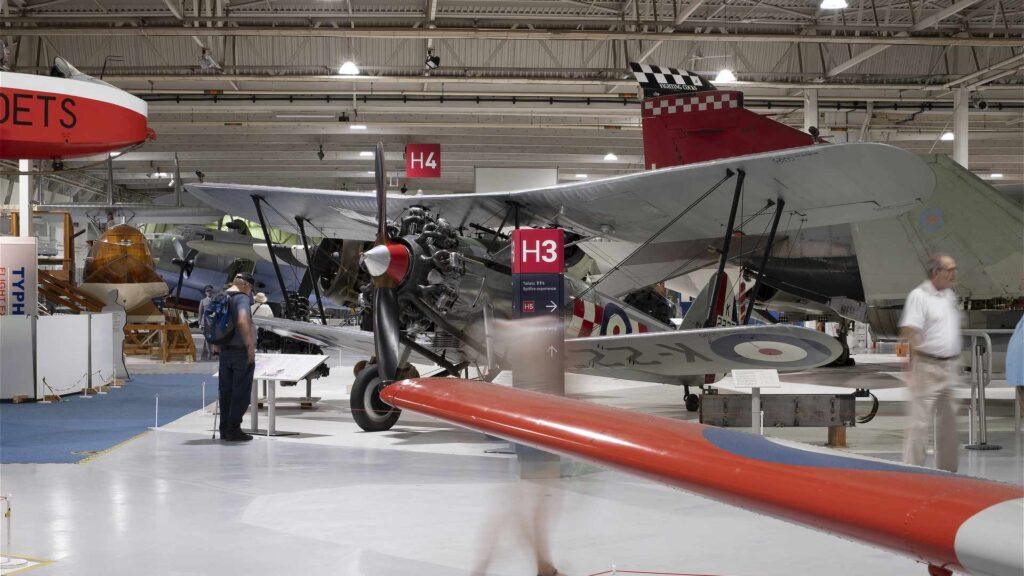 RAF Museum signage in aircraft hangar, with vintage aeroplanes in the background
