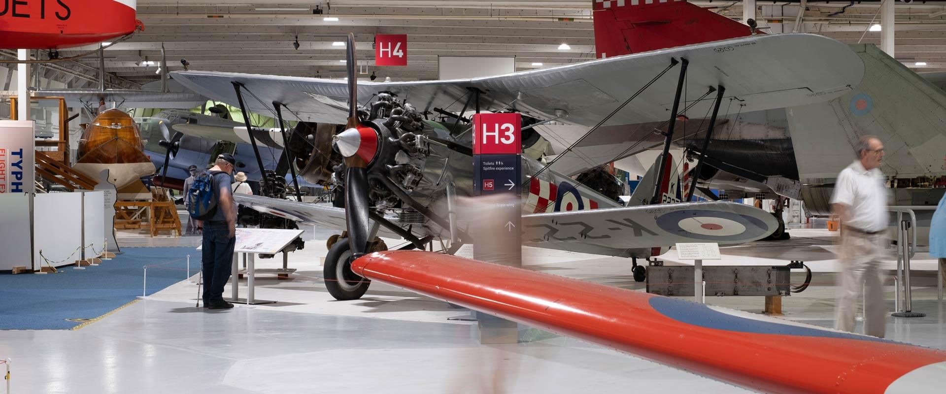 RAF Museum signage in aircraft hangar, with vintage aeroplanes in the background