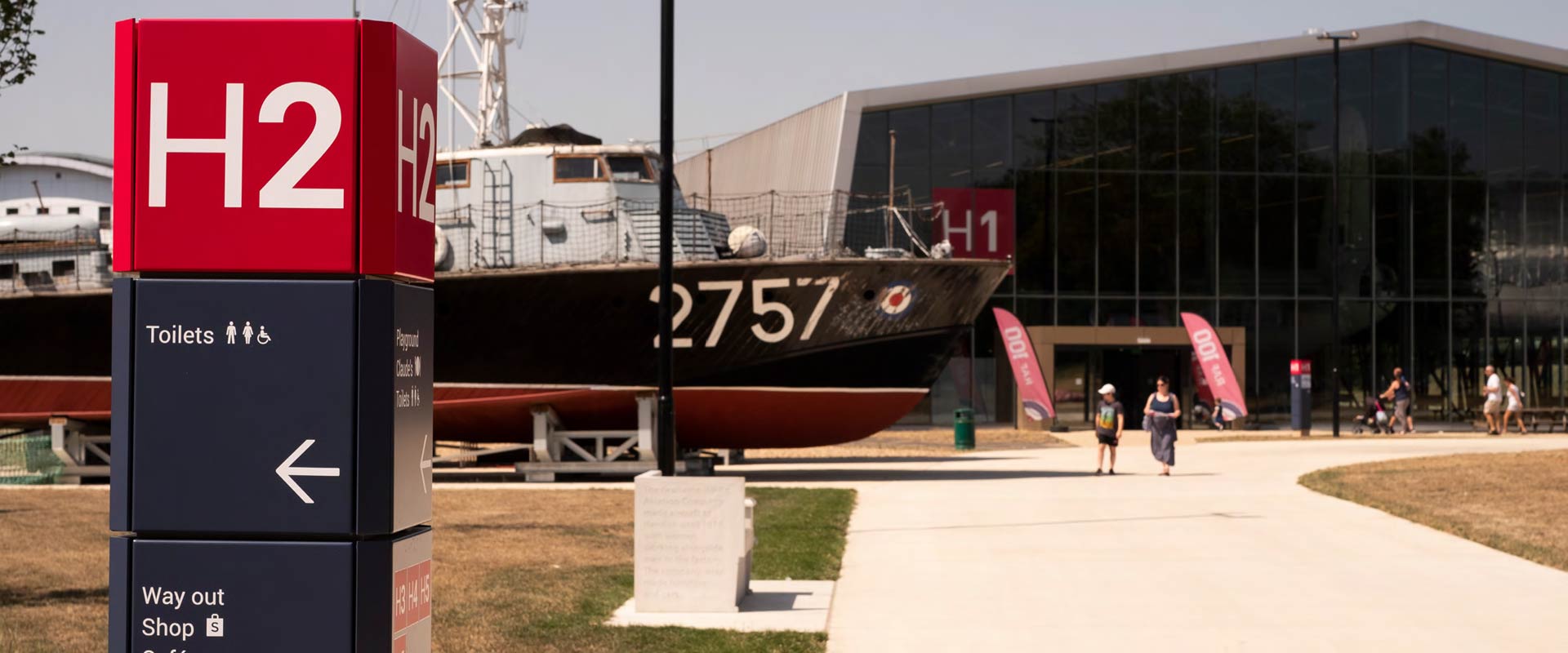 RAF Museum outside signage with boat and aircraft hangar in background
