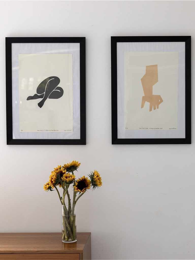 Artwork on wall, and sunflowers in a vase on a cabinet underneath