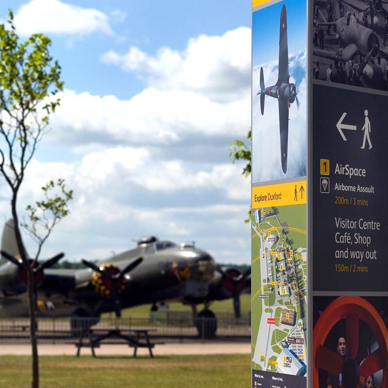 Imperial War Museum, Duxford: map and directions signpost with military aeroplane in background